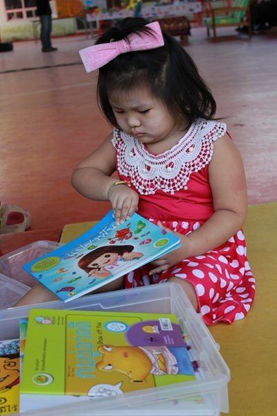 ภาพเด็กสนใจเปิดอ่านหนังสือจากกล่อง