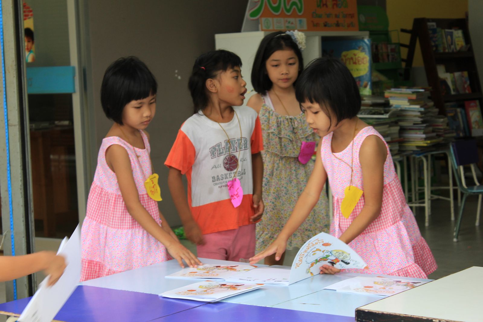 ภาพสาวน้อยน่ารัก 3 คนกำลังดูหนังสือนิทานภาพ อีเล้งเค้งโค้ง